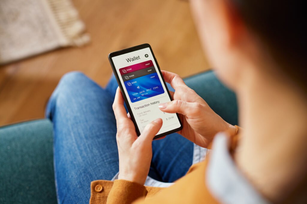 Close up of latin woman hand using smartphone to check the balance of her digital online wallet. Hispanic woman using mobile phone checking payments, account statement and transaction history of her credit cards. Checking expenses of the month on smart phone by internet banking, home finance.